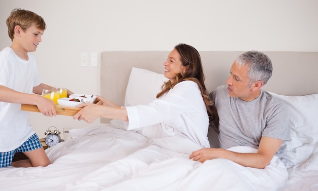 Niño sirviendo desayuno a sus padres