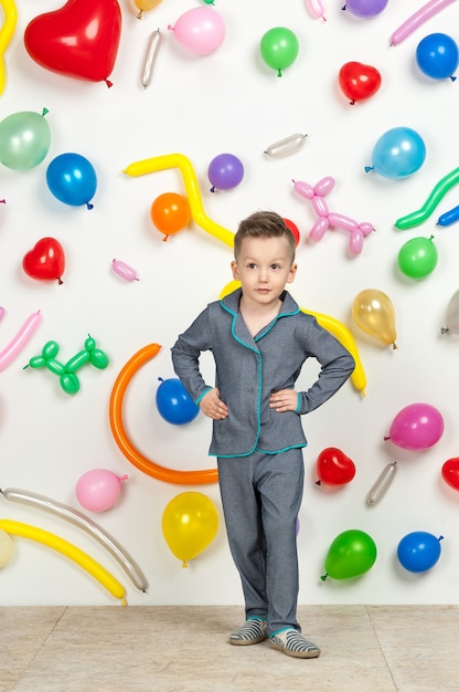 Niño sobre un fondo blanco con globos de colores niño en pijama sobre un fondo blanco con globos