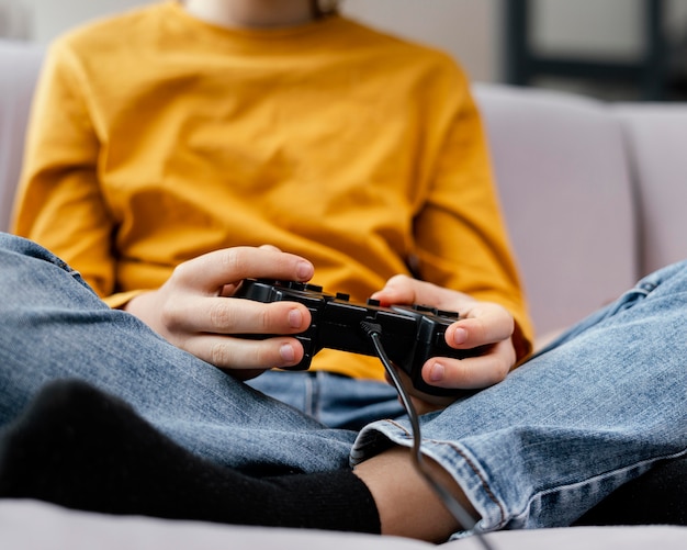 Foto niño en el sofá con joysticks jugando