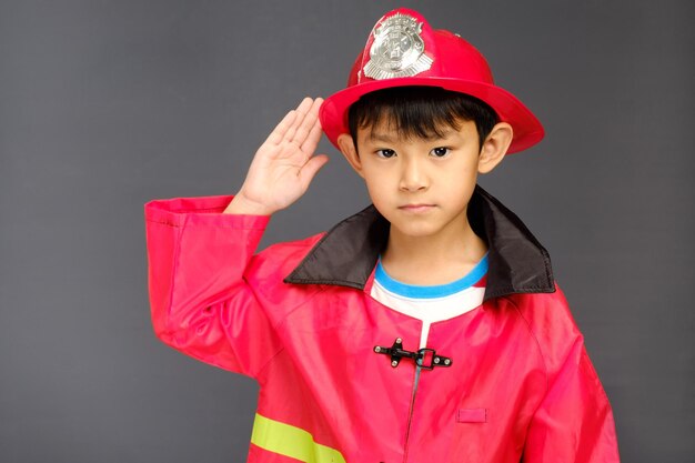 Un niño con un sombrero de bombero y una camiseta que dice bombero.