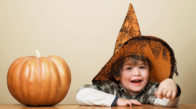 Niño con sombrero de bruja con calabaza de halloween niño pequeño sonriente preparación para la fiesta de halloween