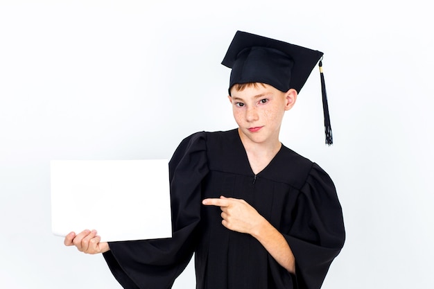 Un niño con un sombrero de estudiante sosteniendo una valla publicitaria vacía.