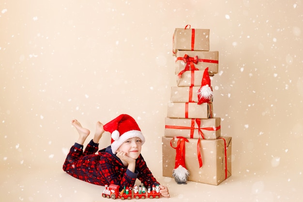 Niño con sombrero de navidad y regalos de navidad concepto de vacaciones de invierno tarjeta de felicitación