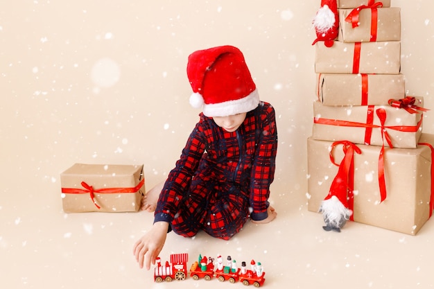 Niño con sombrero de navidad y regalos de navidad concepto de vacaciones de invierno tarjeta de felicitación