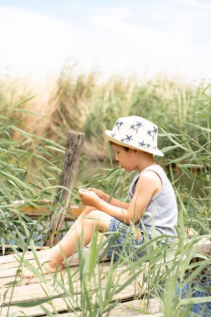 Un niño con sombrero pesca en las cañas.