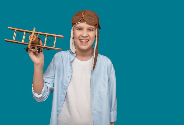 Un niño con sombrero de piloto y con un avión de juguete.