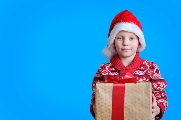 Niño con sombrero rojo con caja de regalo de Navidad en azul