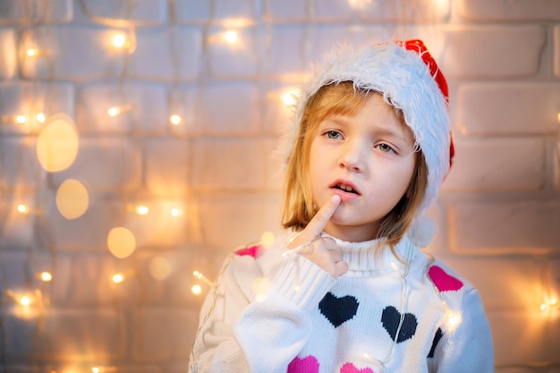 Un niño con un sombrero rojo de Navidad está pensando en algo