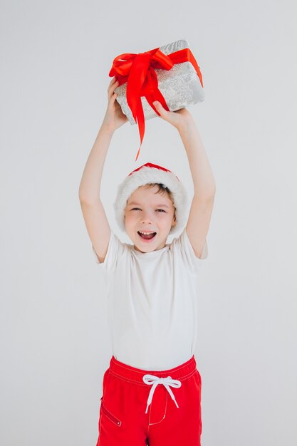 El niño con sombrero rojo de Santa con caja de regalo