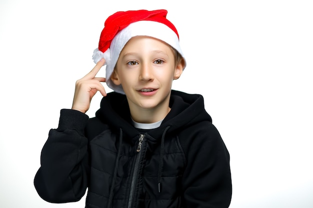 Un niño con un sombrero rojo de Santa se lleva la mano a la cabeza y golpea el sombrero