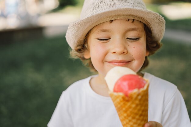 Niño con sombrero sostiene un helado y se ve feliz y sorprendido comida de verano y horario de verano