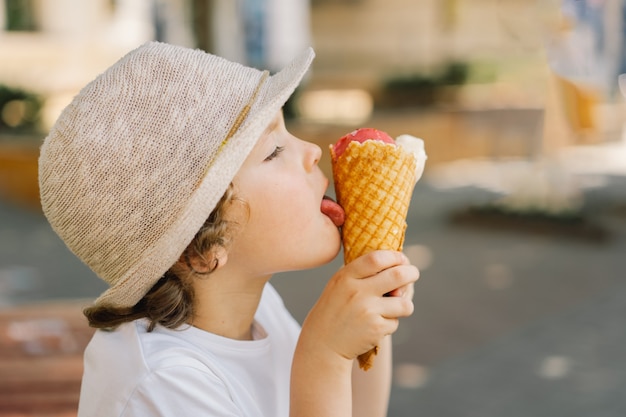 Niño con sombrero sostiene un helado y se ve feliz y sorprendido comida de verano y horario de verano