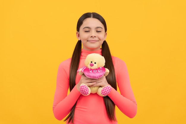 Niño soñador con osito de peluche para el día de san valentín sobre fondo amarillo, sueño