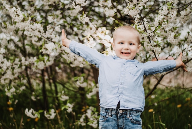 el niño sonríe. un niño en un jardín floreciente. el niño es feliz