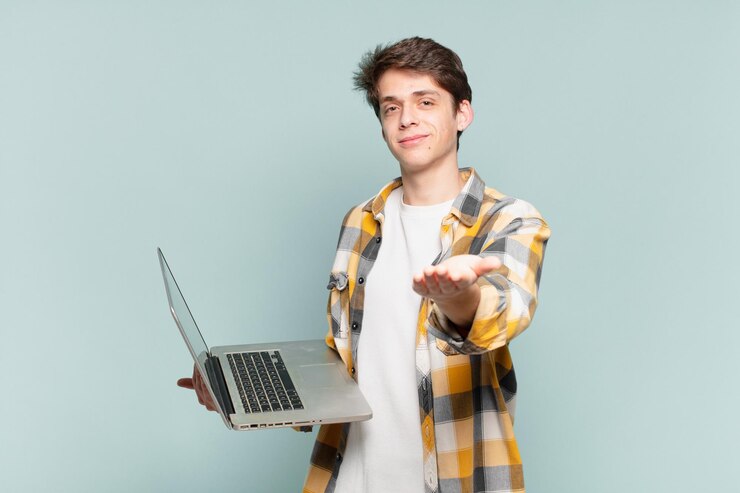 Foto niño sonriendo alegremente con una mirada amistosa, segura y positiva, ofreciendo y mostrando un objeto o concepto. concepto de computadora portátil