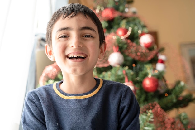 Niño sonriendo en el fondo Árbol de Navidad en casa. niño riendo feliz. niño divertido.