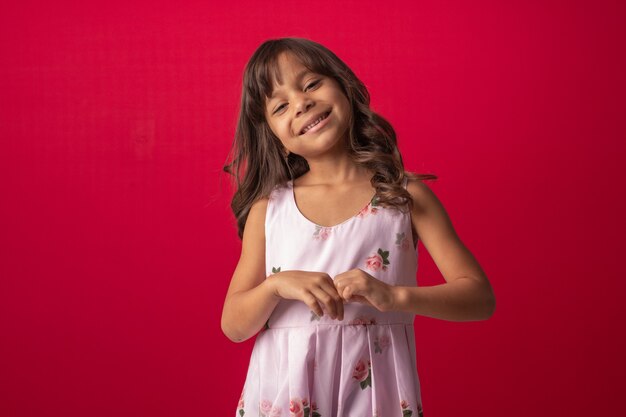 Niño sonriendo en foto de estudio con fondo rojo.