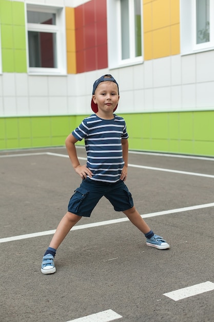 Niño sonriente alegre con gorra azul grande en la escuela