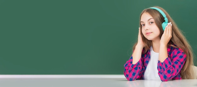 Niño sonriente con auriculares en el accesorio de audio de pizarra Banner de estudiante de colegiala Retrato de alumno de niño de escuela con espacio de copia