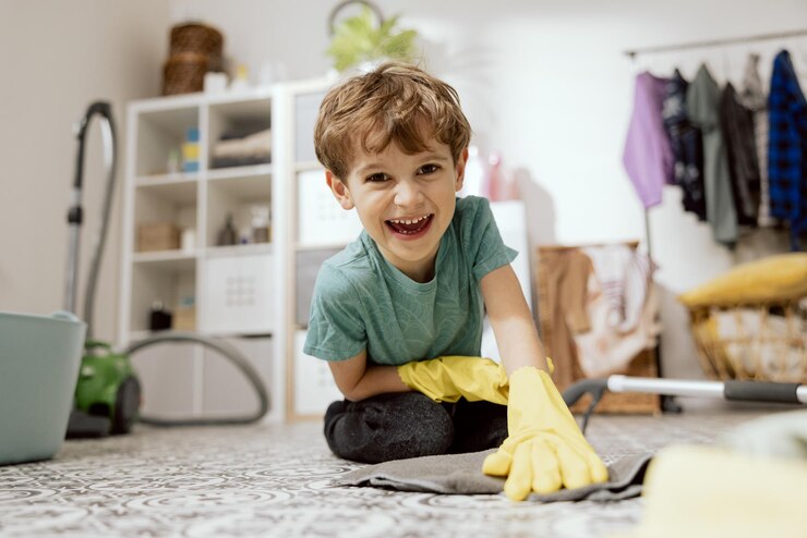 Un niño sonriente ayuda a los padres a fregar el suelo. El niño yace en el baño de la lavandería.