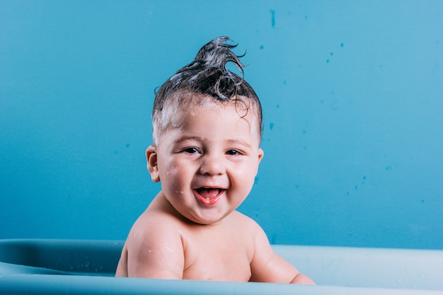 Niño sonriente en el baño con fondo de colores azul