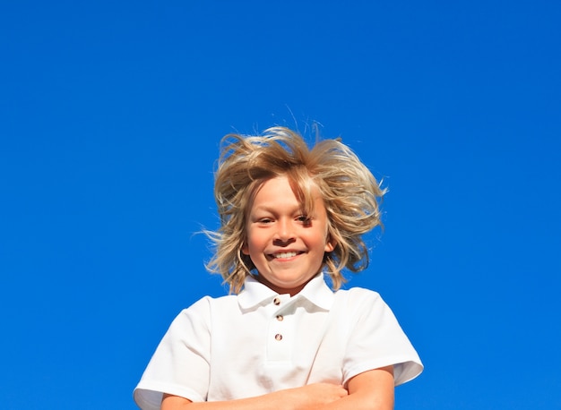 Niño sonriente con los brazos doblados divirtiéndose al aire libre