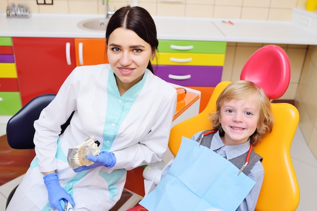 Niño sonriente con cabello rizado claro en el examen en el sillón dental