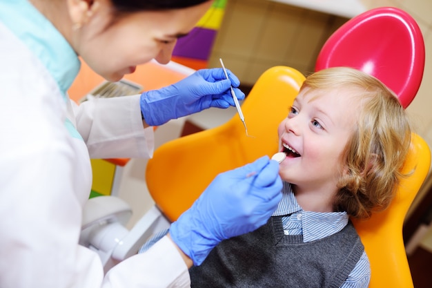 Niño sonriente con cabello rizado claro en el examen en el sillón dental