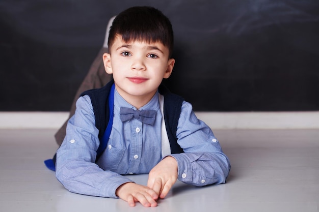 Niño sonriente con camisa azul mirando a la cámara en casa