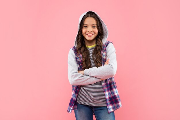 Foto niño sonriente en camisa a cuadros con capucha en hipster de fondo rosa