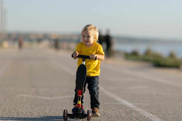 Un niño sonriente se para en la carretera sosteniendo una moto