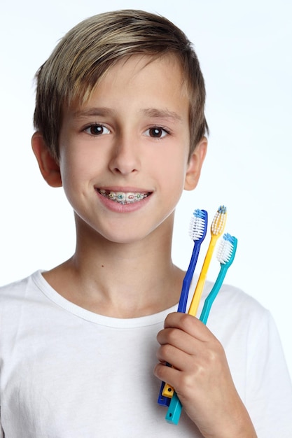 Niño sonriente con cepillo de dientes en la mano aislado sobre fondo blanco.