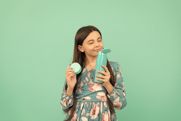 Niño sonriente con champú con olor a cabello largo y cuidado de la piel con crema facial