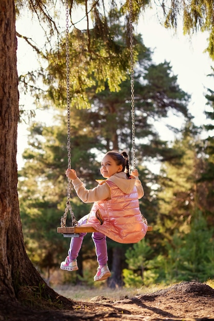 Foto niño sonriente en un columpio en el parque