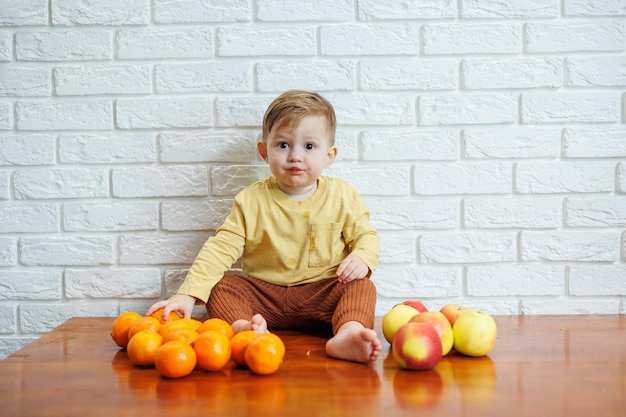 El niño sonriente come una manzana roja fresca y jugosa. Frutas saludables para niños pequeños. El niño come frutas y verduras.