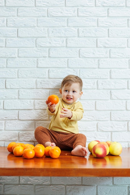 El niño sonriente come una manzana roja fresca y jugosa. Frutas saludables para niños pequeños. El niño come frutas y verduras.