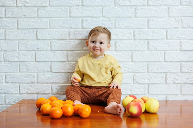 Niño sonriente come una manzana roja fresca y jugosa Frutas saludables para niños pequeños El niño come frutas y verduras