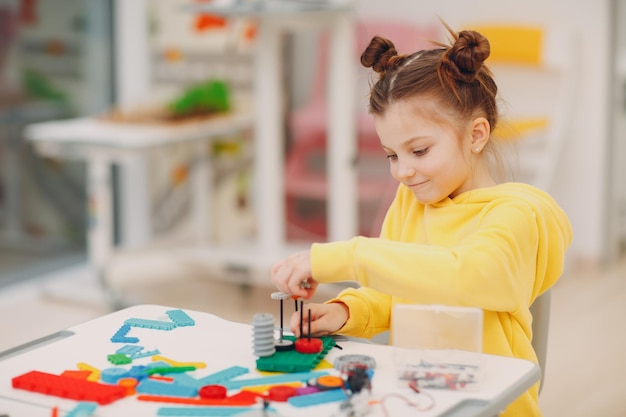 Niño sonriente constructor de niños comprobando juguetes técnicos constructor de robótica para niños ensamblar robot