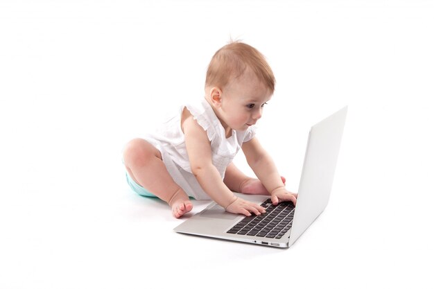 Niño sonriente curioso sentado cerca de la computadora portátil