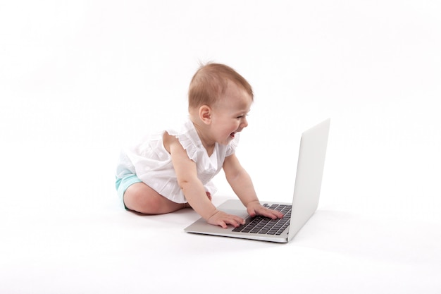 Niño sonriente curioso sentado cerca de la computadora portátil