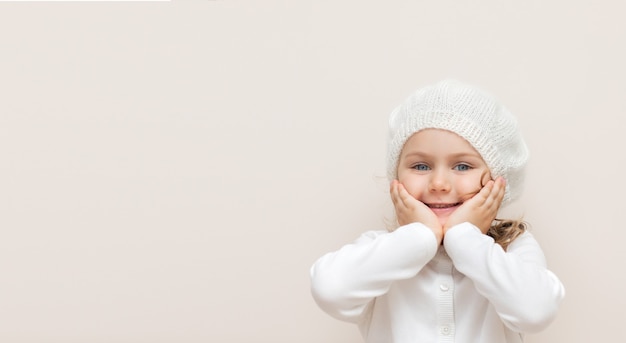 Niño sonriente en diadema tejida de lana hecha a mano y suéter blanco aislado sobre fondo beige