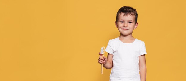 Foto un niño sonriente con dientes sanos sostiene un diente más y un cepillo de dientes en un fondo aislado higiene bucal odontología pediátrica prevención de caries un lugar para su texto