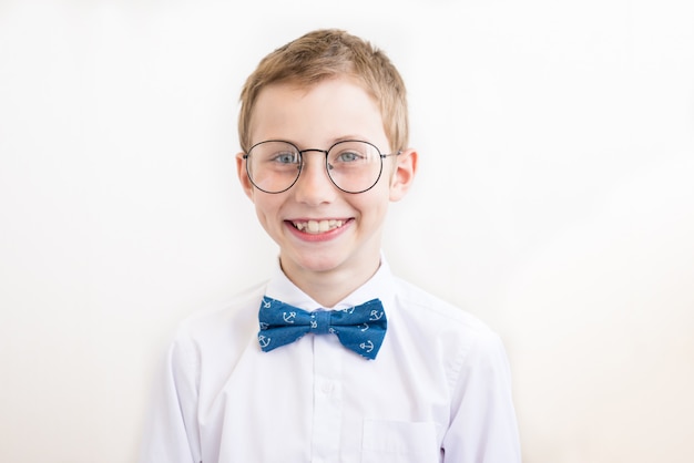 Niño sonriente con gafas en camisa blanca con mariposa sobre un blanco