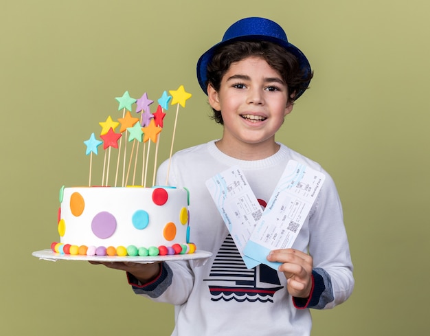 Niño sonriente con gorro de fiesta azul sosteniendo boletos con pastel