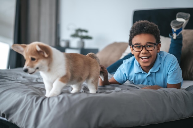 Niño sonriente jugando con un cachorro y mirando contento