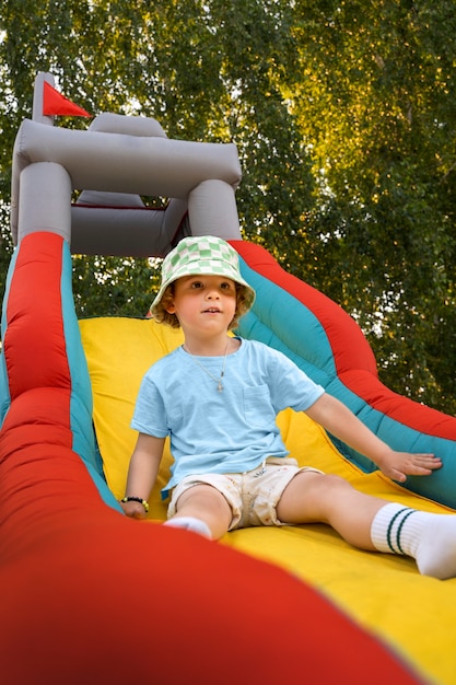 Foto niño sonriente jugando en la casa de rebote tiro completo