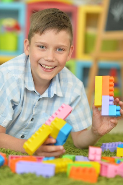 Niño sonriente jugando con coloridos bloques de plástico en el piso