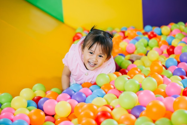 Niño sonriente jugando en la piscina de bolas de colores.