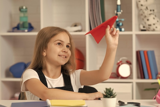 Foto niño sonriente jugar con avión de papel en el aula de la escuela