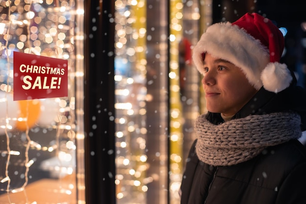 Foto niño sonriente mirando dentro de la tienda desde el exterior por la noche